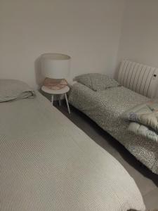two beds in a room with a lamp and a table at anthony meggy in Thiron-Gardais
