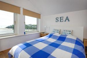 a bedroom with a blue and white bed and windows at 2 Bed in Pwllheli oc-glanab in Abersoch