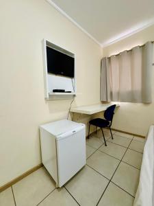 a room with a desk and a tv and a chair at Copaiba Palace Hotel in Bauru