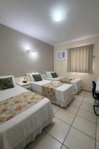 a hotel room with three beds and a window at Copaiba Palace Hotel in Bauru +14 photos