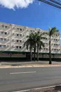 a building with palm trees in front of a street at Copaiba Palace Hotel in Bauru