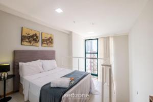 a bedroom with a bed and a large window at Studio w/ pool & barbecue in the building RAQ1609 in Salvador