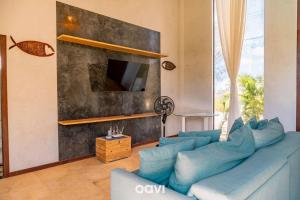 a living room with a blue couch and a tv at Villa Kaitei in São Miguel do Gostoso
