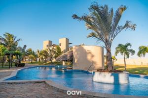 a swimming pool with a palm tree and a building at Villa Kaitei in São Miguel do Gostoso