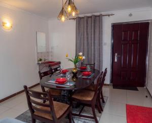 a dining room with a table and chairs and a red door at Perfect Palm Condos-P2 in Nakuru