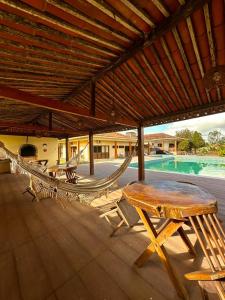 a patio with a table and chairs and a pool at Pousada Estação Verde in Bonito