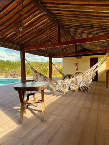 a hammock and a table on a porch at Pousada Estação Verde in Bonito