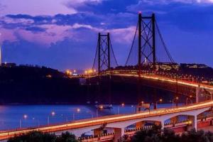 a lit up bridge over a river at night at Blue House - double bed in Almada