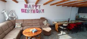 a living room with a couch and a happy birthday sign at Cazare Valea Dinozaurilor in Sibişel