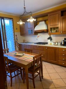 a kitchen with a wooden table with chairs and a stove at Casa del Melograno Outlet in Serravalle Scrivia