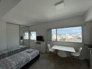 a bedroom with two beds and a desk and a window at Monoambiente Centro in Comodoro Rivadavia