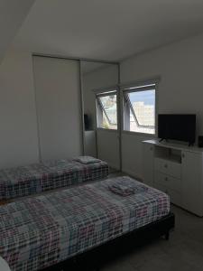 a bedroom with two beds and a television in it at Monoambiente Centro in Comodoro Rivadavia