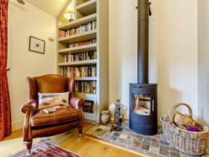 a living room with a chair and a wood stove at 3 Bed in Holt oc-83628 in Blakeney