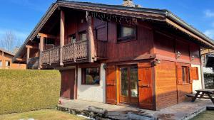a wooden house with a balcony on top of it at Red Fir Chalet in Megève +8 photos