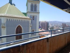 a church with a steeple and a building with a balcony at Maldito Pez Bed & Breakfast in Valparaíso