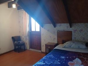 a bedroom with a bed and a chair and a window at Maldito Pez Bed & Breakfast in Valparaíso +1 photo