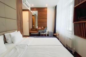 a bedroom with a white bed and a desk at Olivia Rooms in Belgrade