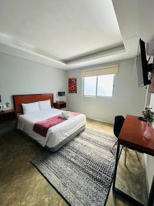 a bedroom with a large bed and a table at Hotel Urban 101 in Chetumal