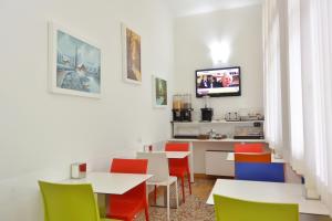 Hotel Trentina في ميلانو: مطعم به طاولات وكراسي وتلفزيون على الحائط