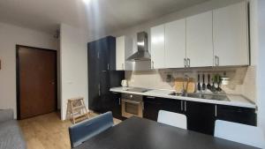 a kitchen with white cabinets and a black counter top at Palazzo Piccolo in Cave del Predil