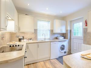 a kitchen with white cabinets and a washer and dryer at 3 Bed in Chathill oc-79566 in Beadnell +9 photos
