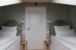 two beds in a room with a door and two stools at Karls Mittenwald - Design Apartments mit Alpenblick & Tagesbar im Herzen von Mittenwald in Mittenwald