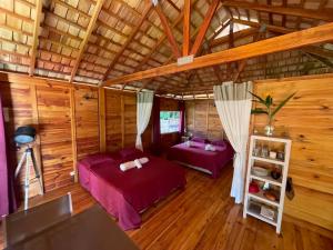 a bedroom with two beds in a room with wooden walls at Lodge ORION - Coté Piscine in Uturoa