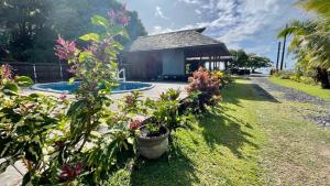 a garden with a gazebo and some flowers at Lodge ORION - Coté Piscine in Uturoa