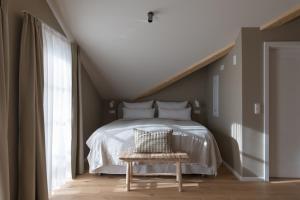 a bedroom with a white bed and a chair at Karls Mittenwald - Design Apartments mit Alpenblick & Tagesbar im Herzen von Mittenwald in Mittenwald