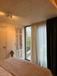 a bedroom with a bed and a large window at de KruidenPoort in Woudrichem