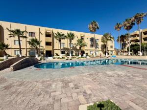 a swimming pool in front of a building with palm trees at Penthouse Water View in Puerto Peñasco