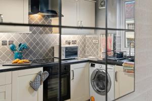 a kitchen with white cabinets and a washer and dryer at Churchill Apartment- 4 Beds- Free Parking- Near NEC BHX & HS2 in Coleshill +40 photos