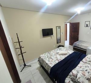 ein Schlafzimmer mit einem Bett und einem Fernseher an der Wand in der Unterkunft Pousada Paulo's in Caruaru