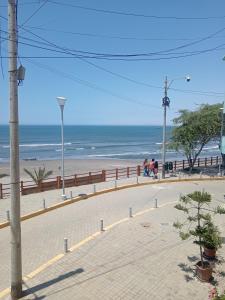 a beach with a fence and people walking on the beach at La Casa Del Hombre in Puerto Chicama