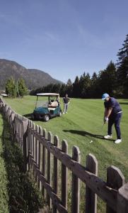 a man playing golf in a field next to a fence at Palazzo Piccolo in Cave del Predil +30 photos