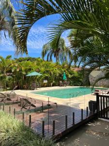 a pool with benches and tables and palm trees at Pousada Recanto da Grande Paz in Alto Paraíso de Goiás