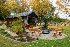 a cabin with benches and a grill in a yard at Apartamenty Greenwood in Staniszów