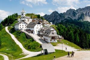 a group of buildings on a hill with a church at Palazzo Piccolo in Cave del Predil