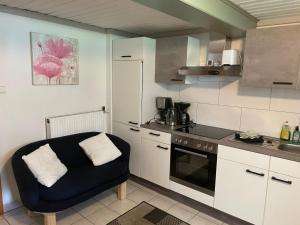 a kitchen with white cabinets and a blue chair in it at Apartment Appartement Wasserfall by Interhome in Stall