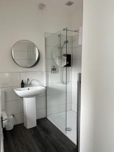 a white bathroom with a sink and a shower at The Rhu Inn in Rhu +28 photos