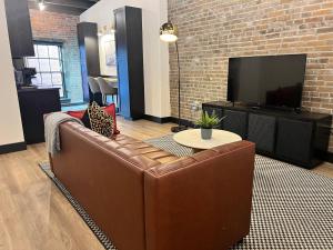a living room with a brown leather couch and a tv at Brick & Bed Riverfront Lofts, T 410 in Saint Louis