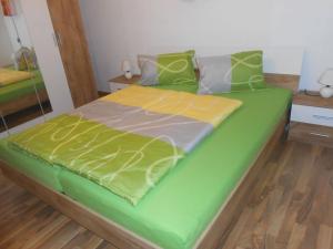 a bed with a green and yellow comforter on it at Apartment Wohnung Michaela in Flattach by Interhome in Flattach