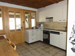a kitchen with white cabinets and a table and a door at Apartment Gurtendörfli by Interhome in Wabern