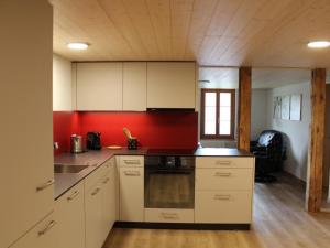 a kitchen with white cabinets and a red wall at Apartment Leinacherhof by Interhome in Seeberg