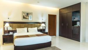 a bedroom with a large bed with a wooden headboard at The Avenue Hotel & Suites in Chittagong