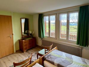 a bedroom with a bed and a desk and windows at Apartment Chalet Hulda by Interhome in Heimenschwand +12 photos