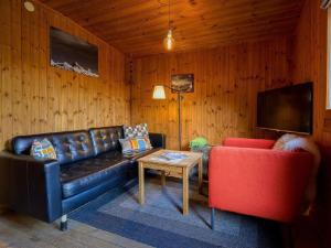 a living room with a black leather couch and a red chair at Apartment Base Camp Evolène by Interhome in Evolène +7 photos