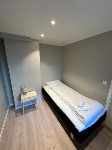 a small bedroom with a bed and a side table at Skolegata 6B, 9404 Harstad in Harstad +1 photo