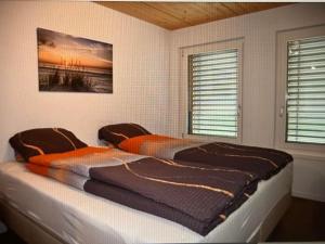 a large bed in a room with two windows at Apartment Panorama-Beatenberg by Interhome in Beatenberg
