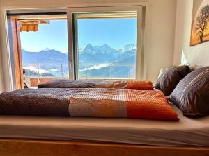 a bed with a large window with a view of mountains at Apartment Panorama-Beatenberg by Interhome in Beatenberg
